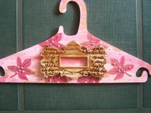 Embellishment glued on front of hanger.