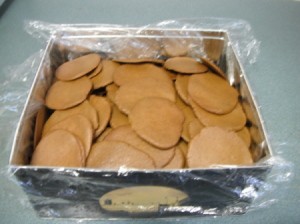 Baked cookies in a box covered with Saran Wrap.