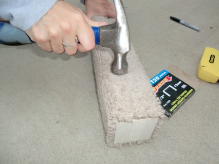 Hammering staples on the post.