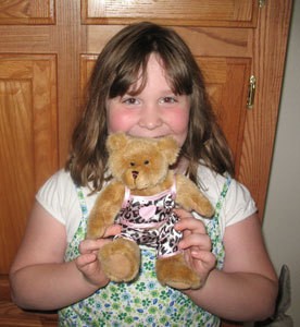 Child holding a small stuffed bear.