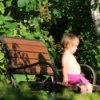 Little girl sitting quietly on a bench, in the garden.