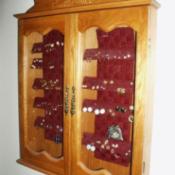Box mounted on wall, filled with earrings, and doors closed.