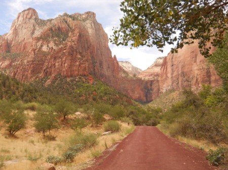 Red road leading towards red rock sandstone formations.