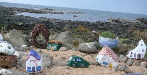 A collection of rocks painted to look like village buildings, overlooking the sea.