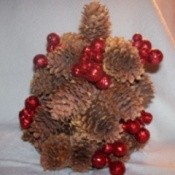 Pinecones glued to CD to resemble a tree and decorated with red berries.