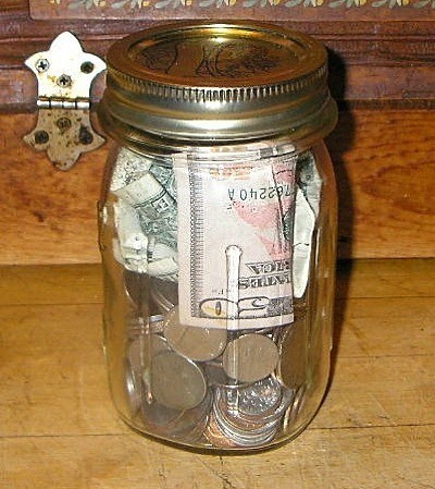 Money Jar full of coins and a $20 bill.