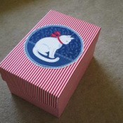 Cardboard box with cat decoration.