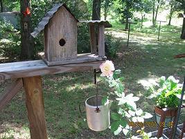 A wooden birdhouse near a rose.