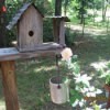 A wooden birdhouse near a rose.