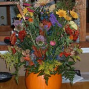 A fall floral display inside a pumpkin vase.