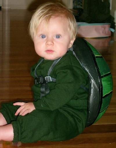 Frontal view of baby with helmet strapped on his back.