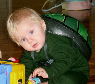 Sitting baby leaning forward with shell on his back.