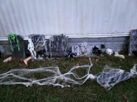 Tombstones outside of home decorated with spider webbing, skeletons, etc.