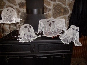 Ghosts made from cheesecloth sitting on woodstove.