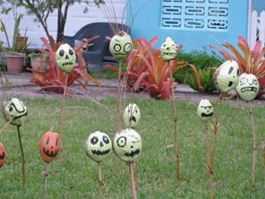Painted gourds on sticks in yard.