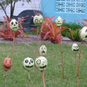 Painted gourds on sticks in yard.