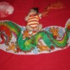 Baby lying on red background with dragon banner.