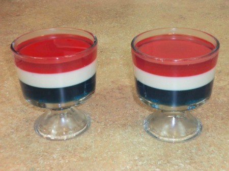 Two clear dishes of red, white, and blue Jello parfait.