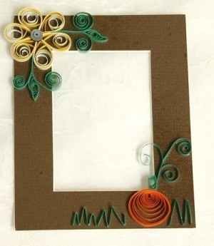 A hand quilled harvest frame with a flower and pumpkin.