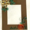 A hand quilled harvest frame with a flower and pumpkin.
