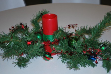 Red pillar candle with greenery for centerpiece.