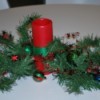 Red pillar candle with greenery for centerpiece.
