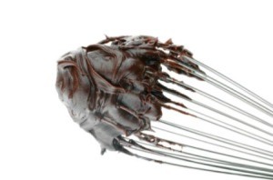 A whisk with hot fudge on it.