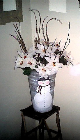 Floral bucket painted with a snowman and filled with white flowers.