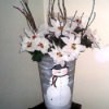 Floral bucket painted with a snowman and filled with white flowers.