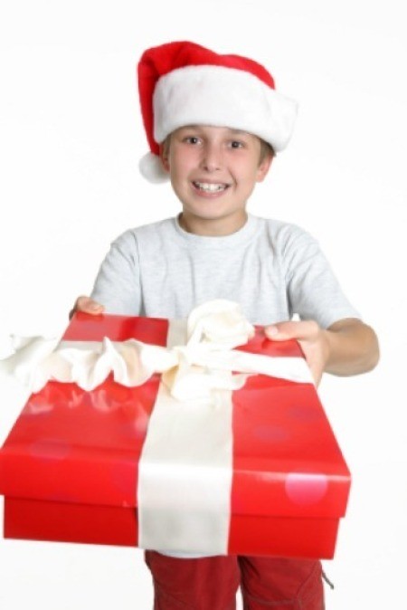 A boy with a Santa hat holding a large package.