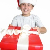 A boy with a Santa hat holding a large package.