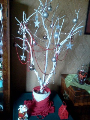 Tree branch painted white and decorated with ornaments.