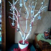 Tree branch painted white and decorated with ornaments.