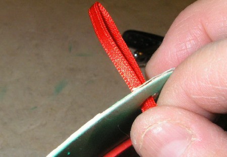 Putting ribbon through hole punched in coaster.