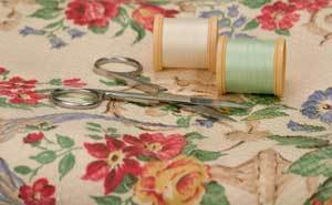 Flowered sheet, spools of thread, and scissors.
