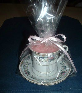 Cup and saucer candle wrapped in clear paper and tied with a pink bow.