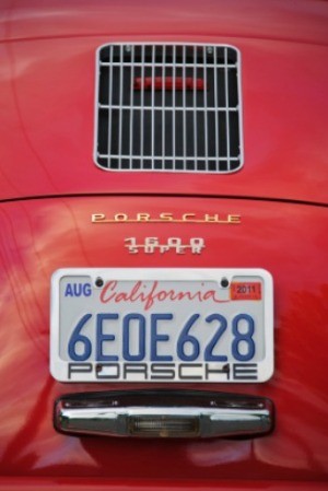 The rear license plate of a red car from California.