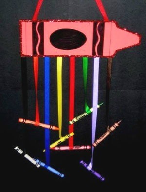 Large paper crayon with colored ribbons hanging from it with crayons glued to the ends.