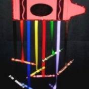 Large paper crayon with colored ribbons hanging from it with crayons glued to the ends.