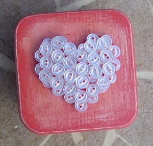 Pink box with white buttons arranged in the shape of a heart.