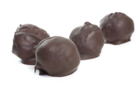 A row of chocolate cover peanut butter balls.