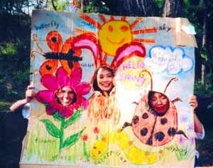 Cardboard drawing of flower, sun, bunny, and ladybug with holes for faces.