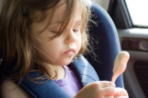 A child eating ice cream in a car.