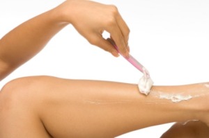 A woman shaving her legs.