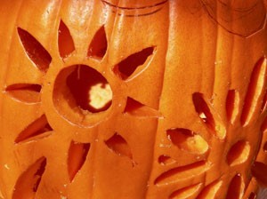 A flower or sun pattern carved into a pumpkin.