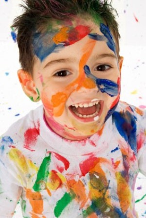 A kid with paint all over his face and clothes.