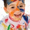 A kid with paint all over his face and clothes.