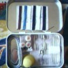A sewing kit inside an empty Altoid's tin.