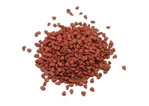 A pile of annatto seed on a white background.
