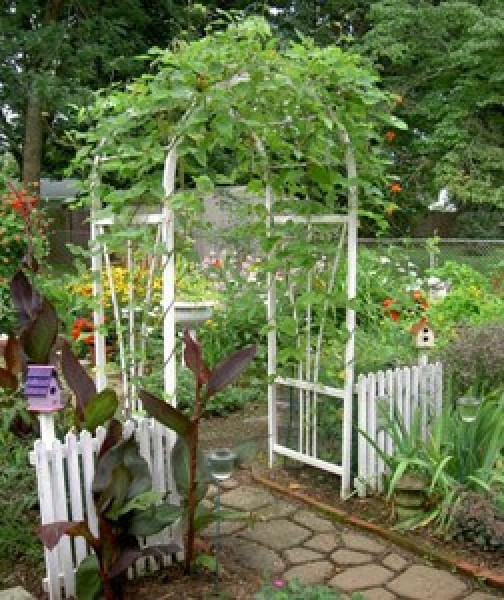 An arbor with recycled fence pieces in a garden.